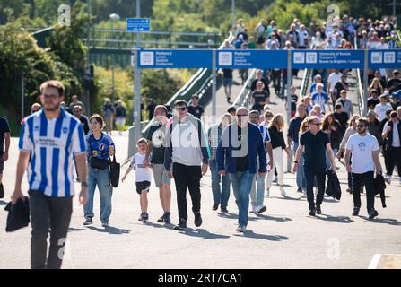 Fußballfans, die aus dem Zug nach Brighton und Hove Albion Football Club's American Express Stadium kommen - 26 August 2023 - Stockfoto