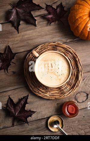 Herbstliches, gemütliches ästhetisches Konzept. Tasse Kürbis-Gewürz-Latte-Kaffee mit Kürbissen und Ahornherbstblättern auf hölzernem Hintergrund. Stockfoto