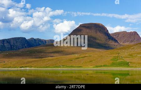 Applecross Scotland Bealach na Ba Berge spiegelten sich im Loch ein rotes Auto auf der Straße Stockfoto