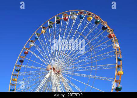 Riesenrad mit farbenfrohen Sitzkissen vor dem Hintergrund des blauen Himmels Stockfoto