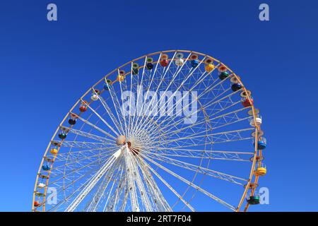 Riesenrad mit farbenfrohen Sitzkissen vor dem Hintergrund des blauen Himmels Stockfoto