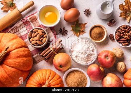 Backhintergrund im Herbst mit Kürbissen, Äpfeln, Nüssen, Zutaten für Speisen und saisonalen Gewürzen auf weißem, kreativem Flachgrund. Kürbis oder Apfel kochen Stockfoto