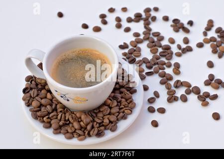 Tasse schwarzer Kaffee und Untertasse mit Kaffeebohnen auf weißem Hintergrund. Stockfoto