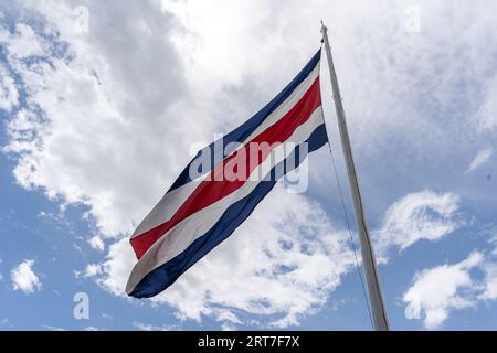 Wunderschöner Blick auf die Costa Rica Flagge mit dem zweihundertjährigen Engel in Cartago, neben den Ruinen und der Basilika - Costa Rica Patriotische Symbole Stockfoto