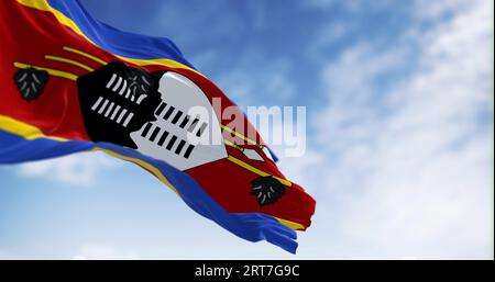 Die Nationalflagge von Eswatini weht einen klaren Tag. Streifen von blau, gelb, rot, gelb, blau mit Swazi-Schild, gefiedertem Stock, Speeren in der Mitte. 3D illustr Stockfoto