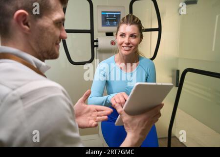 Lächelnde Frau, die im Fitnesscenter ein Tablet durchsucht Stockfoto