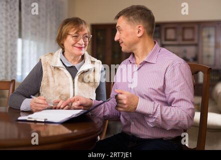 Frau mit Sohn, die Dokumente ausfüllt Stockfoto
