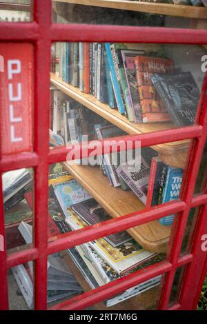 Bücher werden durch das Fenster einer öffentlichen Telefonbox im Cotswolds-Dorf Sheepscombe am 8. September 2023 in der Nähe von Stroud, England, gesehen. Seit Anfang des 17. Jahrhunderts war Sheepscombe wie viele der Cotswold-Städte in der Gegend und dem benachbarten Painswick an der Tuchherstellung beteiligt. Stockfoto