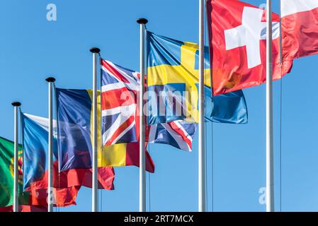 Flaggen europäischer Länder auf Fahnenmasten, die im Wind gegen den blauen Himmel fliegen Stockfoto