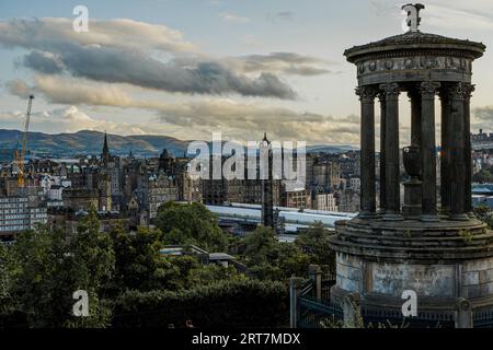 Panoramablick auf Edinburgh mit dem Dugald Stewart Monument auf dem Calton Hill. Der Sonnenuntergang erleuchtet die historische Skyline. Perfekt für Reisen und kulturelle Inhalte. Stockfoto