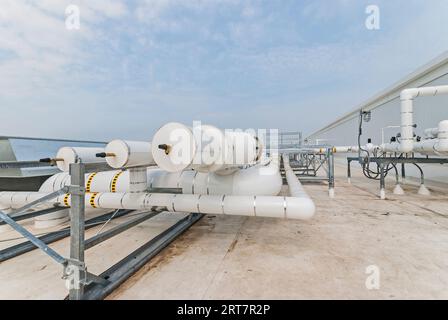 Weiß isolierte Rohrleitungen auf dem Dach des Kühlhauses für den Transport von Flüssigkeiten und Gasen in der Ammoniak-Kreislauf-Kühlung. Stockfoto