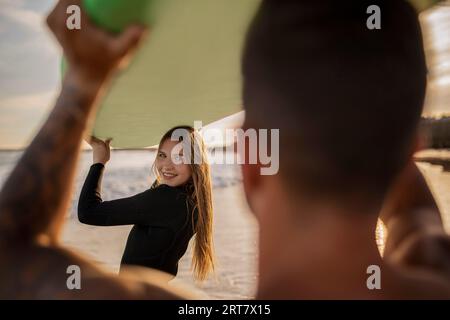Schöne Junge Frau, Die Mit Ihrem Freund Am Strand Surft Stockfoto