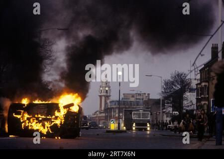 Brixton Unruhen 1981 Großbritannien. Entführt brennendes Auto, das von den Randalierern in Brand gesetzt wurde. Brixton Rathaus Uhrenturm im Hintergrund. Brixton South London Großbritannien 1980er Jahre England HOMER SYKES. Stockfoto