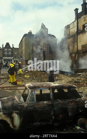 Brixton Unruhen 1981 Großbritannien. Am Tag nach der Feuerwehr stellte die Feuerwehr sicher, dass die brennenden Gebäude vollständig sicher sind. Ausgebranntes zerstörtes Gebäude entführt Burnout Auto. Brixton South London Großbritannien 1980er Jahre England HOMER SYKES. Stockfoto