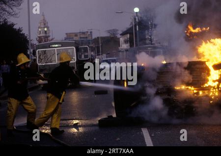 Brixton stößt in den 1980er Jahren auf Großbritannien auf. Feuerwehrleute nehmen an einem brennenden Auto Teil, das von den Randalierern angezündet wird. Brixton Rathaus Uhrturm im Hintergrund. Brixton South London Großbritannien April 1981 England HOMER SYKES. Stockfoto