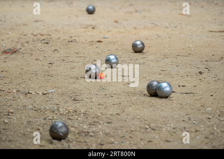 Petanque Ball Boules Schüsseln auf einem Staubboden, Foto beim Aufprall. Petanque-Spiel auf dem Boden. Kugeln und einen kleinen Holzheber. Stockfoto