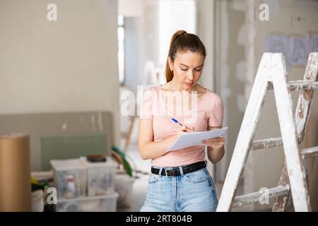 Frau überprüft den Plan des Hauses, das gerade renoviert wird Stockfoto