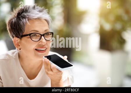 Nahaufnahme einer Reifen Geschäftsfrau, die Voicemail auf dem Smartphone aufnimmt Stockfoto