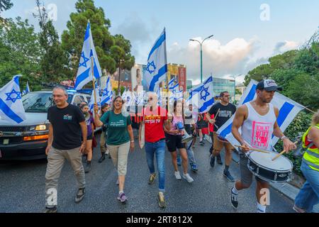 Haifa, Israel - 9. September 2023: Menschen marschieren mit verschiedenen Schildern und Flaggen. Woche 36 des Protestes gegen eine umstrittene Justizreform. Haifa, Isra Stockfoto