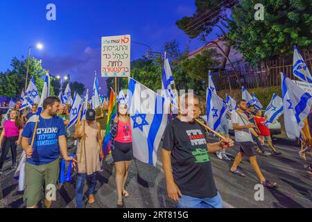 Haifa, Israel - 9. September 2023: Menschen marschieren mit verschiedenen Schildern und Flaggen. Woche 36 des Protestes gegen eine umstrittene Justizreform. Haifa, Isra Stockfoto