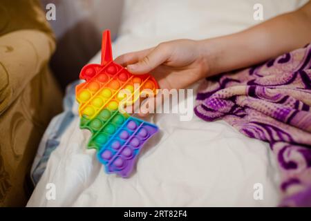 Teenager hält ein Getränk in Form eines Einhorns in der Hand. Auf dem Bett liegend Kind mit einem Anti-Stress-Spielzeug. Stockfoto