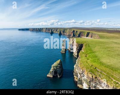 Luftaufnahme der zerklüfteten Küstenlandschaft am Duncansby Head mit Felsturm, dahinter die Duncansby Stacks, County Caithness, Schottland, Great Stockfoto