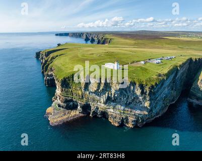 Blick aus der Vogelperspektive auf die zerklüftete Küstenlandschaft von Duncansby Head mit dem Leuchtturm und der Felsformation Duncansby Stacks dahinter, Schottland Stockfoto