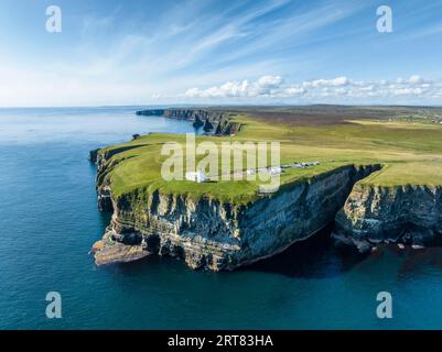 Blick aus der Vogelperspektive auf die zerklüftete Küstenlandschaft von Duncansby Head mit dem Leuchtturm und der Felsformation Duncansby Stacks dahinter, Schottland Stockfoto