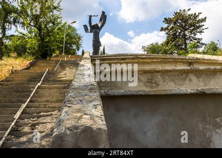 Monument to the Unknown Soldier in Vake Park, Tiflis, Georgia: Verwitterte Stufen, die zu einem Sockel führen, auf dem eine Bronzestatue einer Frau mit erhobenen Armen zu sehen ist. Das sowjetische Kriegsdenkmal erinnert an die georgischen Soldaten, die im Zweiten Weltkrieg gefallen sind; Sockel und Stufen sind schwer beschädigt und mit Graffiti bedeckt. Der Sockel ist mit Graffiti bedeckt. Eine Treppe führt zum Sockel. Bezirk Vake, Tiflis, 0162, Georgia Stockfoto
