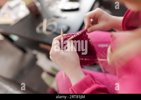 Hände der jungen Frau Stricken Socken zu Hause mit rosa Wolle Stockfoto
