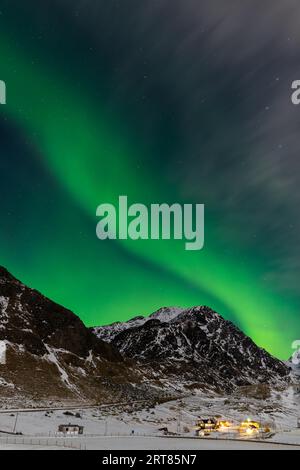 Spektakuläre, tanzende grüne, kräftige Nordlichter über dem berühmten runden Sandstrand in der Nähe von Haukland auf den Lofoten-Inseln in Norwegen im klaren Winter Stockfoto