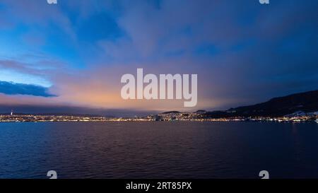 Annäherung an die beleuchtete norwegische Stadt Trondheim in der frühen Morgendämmerung gesehen Vom Meer auf dem Kreuzfahrtschiff Stockfoto