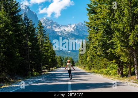 Eine junge Touristenfrau, die auf der Straße im Valbona-Tal, Theth-Nationalpark, Albanischen Alpen, Valbona Albanien spaziert Stockfoto