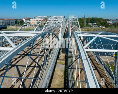 Neue dreifach gebundene Eisenbahnbrücke mit vier Gleisen, Laufsteg und Fahrradroute über die Weichsel in Krakau, Polen. Drohnenansicht aus der Luft Stockfoto