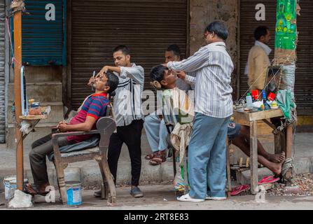 Neu Delhi. September 2023. Straßenbarber rasieren ihre Kunden in Neu-Delhi, Indien. Am 11. September 2023. Quelle: Javed Dar/Xinhua/Alamy Live News Stockfoto