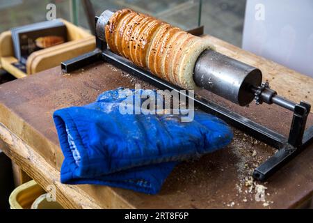 Prag, Tschechische Republik, 18. März 2017: Das berühmte tschechische Gebäck Trdelnik wird in einer Straßenbäckerei gebacken. Trdelnik, auch Trdlo genannt, ist eine zuckersüße Süßigkeit Stockfoto