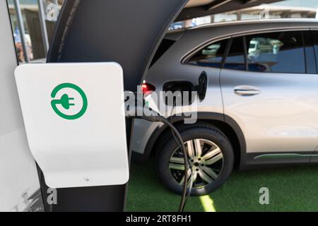 Nahaufnahme eines Elektroautos mit angeschlossenem Kabel und Ladestation. Stockfoto