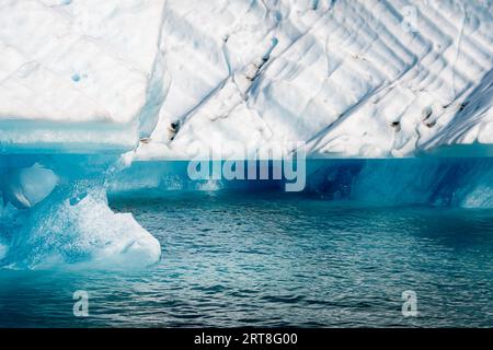 Nahaufnahme eines Eisbergs. Am oberen Bildrand befindet sich das Eisstück, am unteren Bildrand das fließende Wasser. Stockfoto