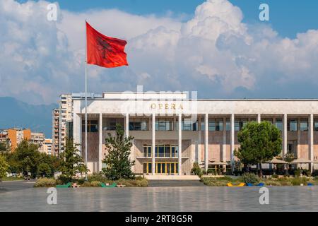 Kulturpalast oder Oper auf dem Skanderbeg-Platz in Tirana und die Flagge Albaniens, die sich im Wind bewegt Stockfoto