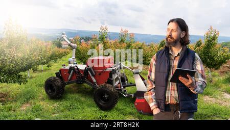 Der Landwirt steuert autonome Roboter in einem Obstgarten. Intelligentes Landwirtschaftskonzept... Stockfoto