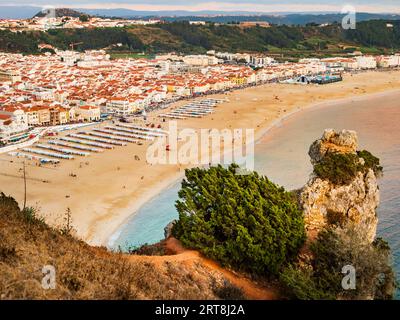 Fantastischer Blick auf den Strand von Nazare (praia de Nazare) mit farbenfrohen Badehütten und dem Stadtbild des Dorfes im Hintergrund, Portugal Stockfoto