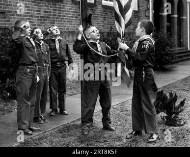 Junge Mitglieder eines Cub Scout-Geländes nehmen in den 1950er Jahren an einer US-amerikanischen Flaggenhisserungszeremonie Teil Stockfoto