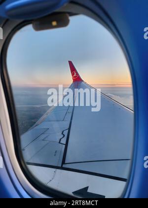 Istanbul, Türkei - 14. Juni 2023: Flugzeugfenster mit Sonnenuntergang in Orange. Ein Flug von Turkish Airlines mit sichtbarem Logo Stockfoto