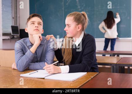 Nachdenkliche junge Studenten beim Schreiben von Notizen im Klassenzimmer Stockfoto