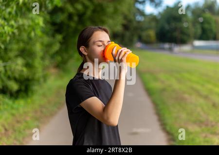 Nimm eine Wasserflasche in der Nähe des Laufers für Mädchen. Fitness-Frau, die nach dem Lauftraining eine Pause macht. Stockfoto