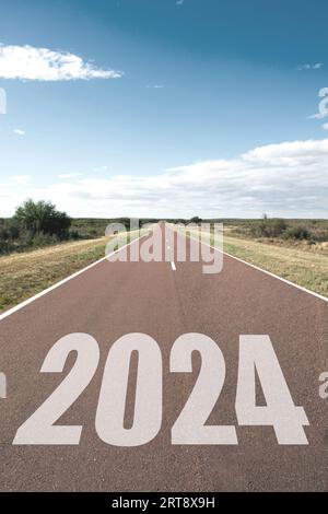 2024 Konzept des neuen Jahres, Beginn. Eine lange, gerade Straße, die in eine ländliche Landschaft führt Stockfoto