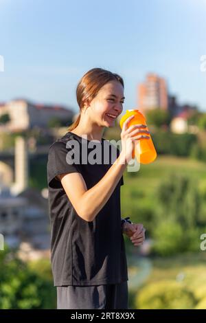 Nimm eine Wasserflasche in der Nähe des Laufers für Mädchen. Fitness-Frau, die nach dem Lauftraining eine Pause macht. Stockfoto