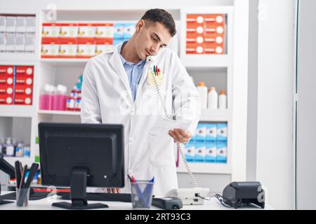 Junger hispanic-Mann Apotheker im Gespräch auf telefonische Lesung Rezept in der Apotheke Stockfoto