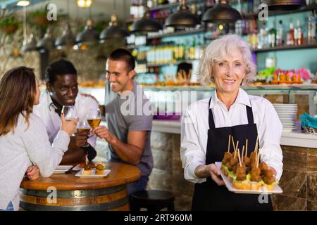 VIW über die europäische alte Dame, die Tapas in einem Pub hält Stockfoto