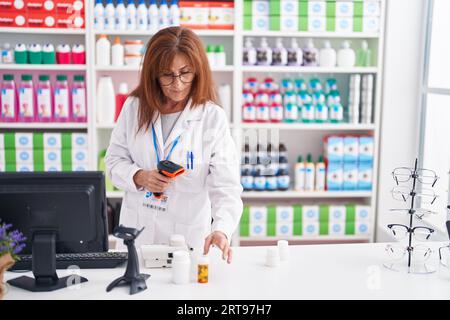 Frau mittleren Alters Apotheker Scannen Pillen Flasche in der Apotheke Stockfoto